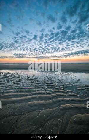 Ripples in the sand of the beach during a colorul sunset at the dutch coast Stock Photo