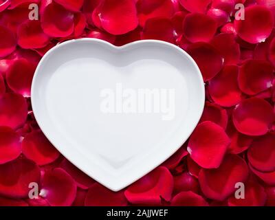 Heart-shaped plate on rose petals Stock Photo