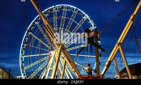 Kids bungee jumping next to a large ferris wheel at a summer festival in Dresden, Germany Stock Photo
