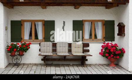 Cute little patio, bench and flowers in a typical Bavarian home in the Oberammergau region of Germany.  Famous Passion Play town. Stock Photo