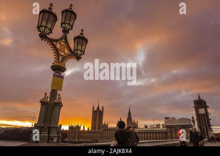 Westminster, London, 4th Jan 2020. Tourists and Londoners enjoy the beautiful sunset on Westminster Bridge with Parliament in the background. Calm and dry conditions in London at the end of a beautifully sunny day across the capital. Stock Photo