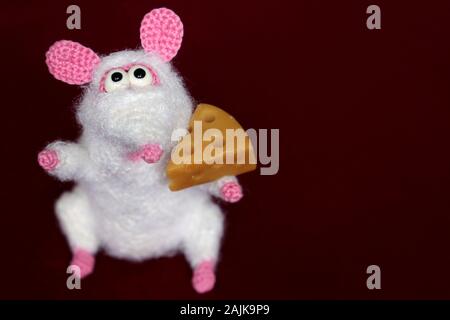 White knitted toy rat with piece of cheese on red background, New Year card. Chinese Year of Rat, Zodiac symbol 2020 Stock Photo