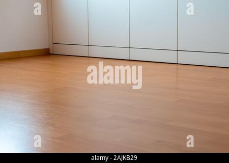 A low angle view of wooden laminate flooring in a bright spacious room with wall-to-wall closet Stock Photo
