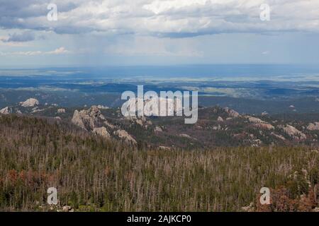 The back side of the large rock formation that is Mount Rushmore on the left with a parking area on the far right as seen from Black Elk Peak in Custe Stock Photo