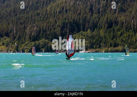 People windsurfing and kite surfing in a lake during a sunny summer day Stock Photo