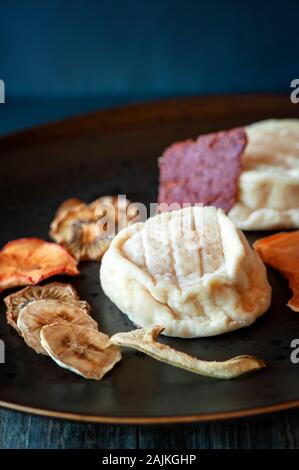 Delicious white soft round cheese with mold with fruit chips. Copy space. Selective focus. Stock Photo