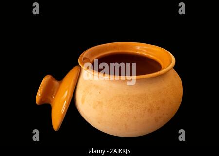 Clay pot with lid for preparation of the food insulated on black background Stock Photo