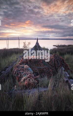 old abandoned boat covered in fishing nets Stock Photo