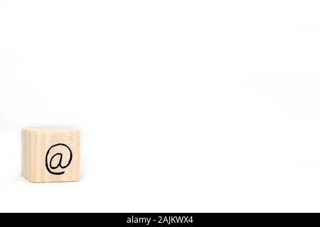 Wooden cube with a commercial At Sign symbol isolated on white background, space for text Stock Photo