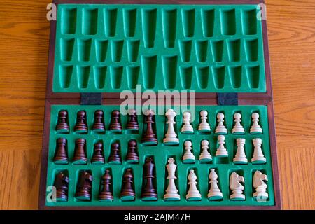 A wooden chess set in its box, view from above with brown background. The picture shows old traditional hand-made chess in a box. Stock Photo