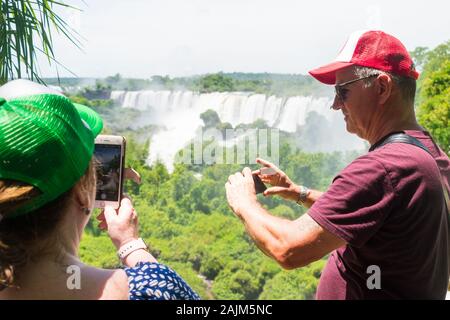 Puerto Iguazu, Argentina - Circa November 2019: Older couple taking pictures with their smartphones at the Iguazu National Park Stock Photo