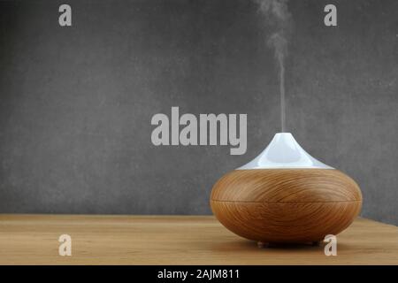 Aroma oil diffuser on wooden table and grey background Stock Photo