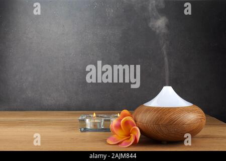 Aroma oil diffuser, candles and flowers on wooden table Stock Photo