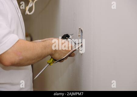 Hands professional on installing electrical outlets with electrical wires and connector installed in plasterboard drywall Stock Photo