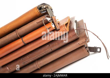 A stack of leather-bound journals, notebooks, cases, and wallets set on a plain white background. Stock Photo