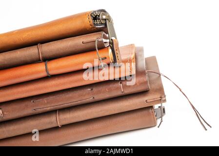 A stack of leather-bound journals, notebooks, cases, and wallets set on a plain white background. Stock Photo