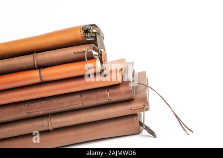 A stack of leather-bound journals, notebooks, cases, and wallets set on a plain white background. Stock Photo
