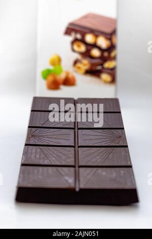 Dark chocolate with whole hazelnuts isolated on white background Stock Photo