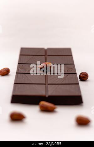 Dark chocolate with whole hazelnuts isolated on white background Stock Photo
