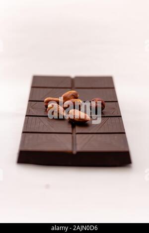 Dark chocolate with whole hazelnuts isolated on white background Stock Photo