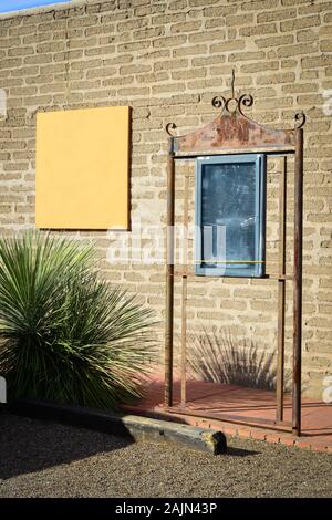 A scene with an empty ornate metal signboard frame with a large blank square sign on an old adobe building in the artisan town of Tubac, AZ, USA Stock Photo