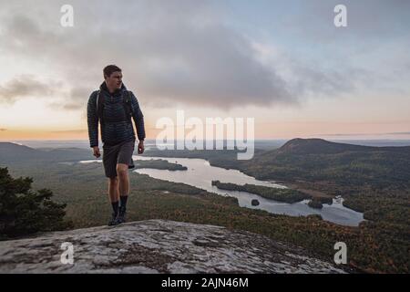 male hiker walks along Appalachian Trail with view at sunrise in Maine Stock Photo
