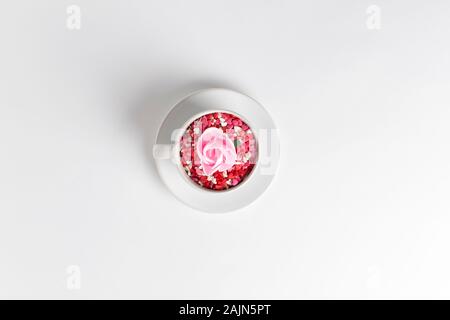 white cup of coffee on a white background filled with heart shaped confetti. selective focus. valentine day concept Stock Photo