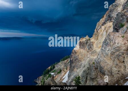 Dark Blue Storm Clouds Over Crater Lake With Rays Reflecting on Surface Stock Photo