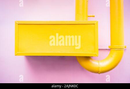 Catchy abstract minimalistic style painted yellow piping on surface of pink pastel colored wall Stock Photo