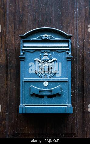 Antique vintage style blue rectangular mailbox hanging on brown wooden door Stock Photo