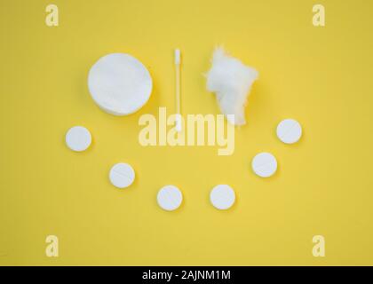 Clean white cotton pads, ear stick and pills that forms smiley face, healthcare concept, yellow background Stock Photo