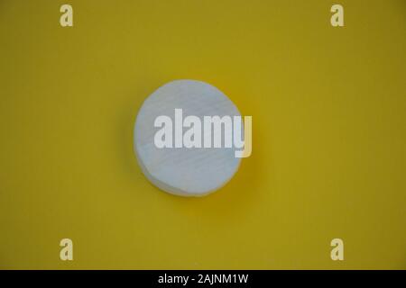 Clean white cotton pad for cleaning on the make-up, on yellow background Stock Photo