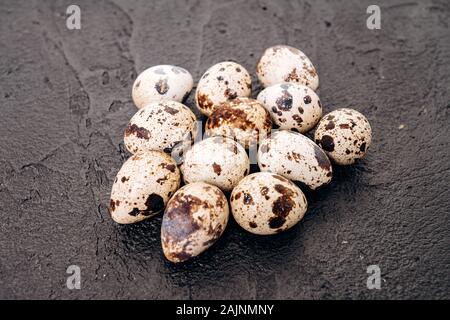 Quail eggs on a black background. Several quail eggs lie on a black stone background Stock Photo