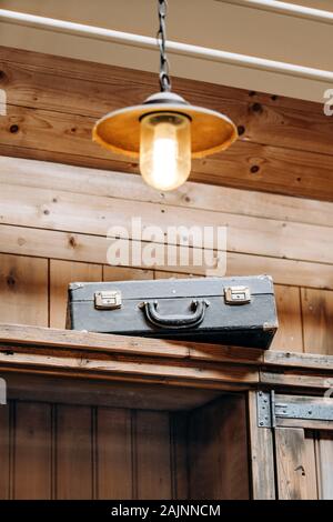 An old battered suitcase on a shelf in the dust. Vintage travel bags are on a shelf. Retro bulky Luggage. Image done in grunge style on rough dirty te Stock Photo