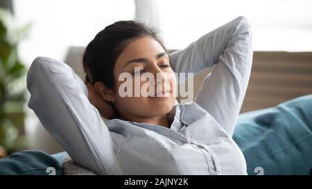 Serene indian woman resting on comfortable sofa hands behind head Stock Photo