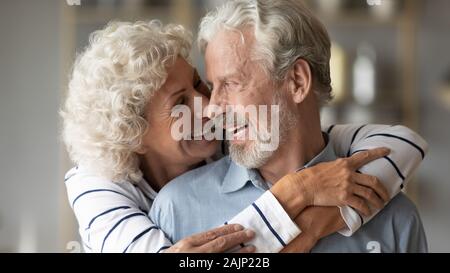 Closeup image elderly wife hug from behind beloved husband Stock Photo