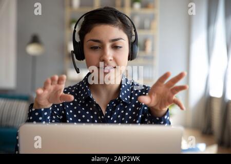 Indian woman teacher wear wireless headset video calling on laptop Stock Photo