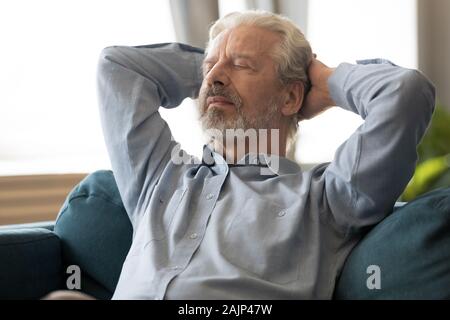 Senior man leaned on couch put hands behind head resting Stock Photo