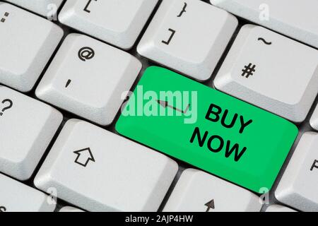 A keyboard with Buy Now written in black lettering on a green enter key. Internet online shopping and investments concept. England, UK, Britain Stock Photo