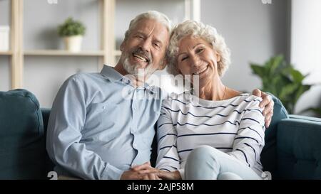60s loving couple sitting in living room posing looking at camera Stock Photo