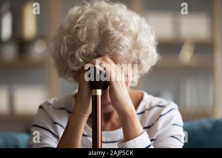 Close up image woman bowed her head holding walking stick Stock Photo