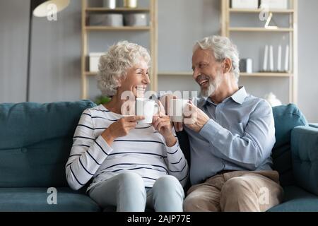 Pretty 70s hoary spouses holding coffee cups laughing enjoy talk Stock Photo