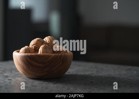 inshell walnuts in olive wood bowl on terrazzo countertop, shallow focus Stock Photo
