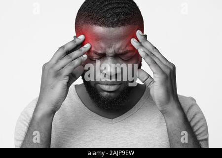 Afro guy with headache touching his temples, emotional black and white photo Stock Photo