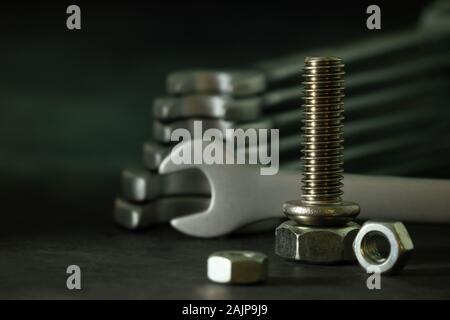Bolt nuts and wrench on cement floor in darkness. Closeup and copy space for text. Concept of mechanical engineering jobs. Stock Photo