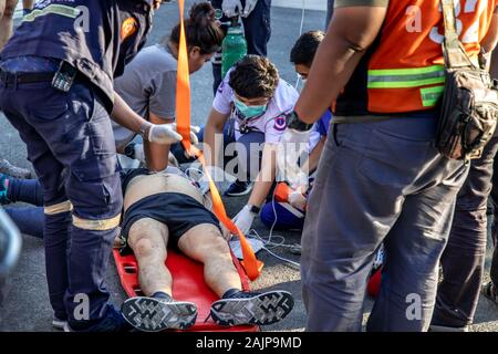 Bangkok, Thailand - Jan 05, 2020 : First Aid Emergency CPR, Woman giving CPR to unconscious man has Heart Attack or Shock, While runner jogging outdoo Stock Photo
