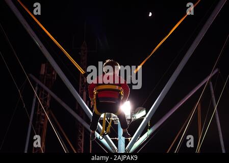 Child at a fair jumping on a Bungee Trampoline during the night. Stock Photo