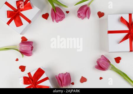 Pink tulip flowers gifts and red hearts composition on white background top view with copy space. Valentine's day, birthday, wedding, Mother's day con Stock Photo