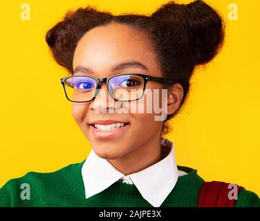 Optical Shop. Portrait of black schoolgirl in glasses looking at camera isolated over yellow background Stock Photo