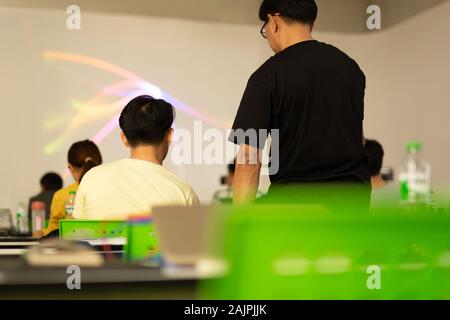 Back view of teacher explaining to students in a class. Stock Photo